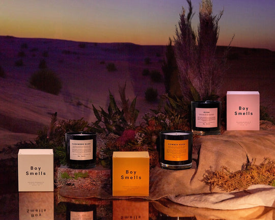 Image of kush collection candle vessels and boxes with sunset desert scape in background