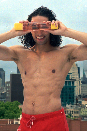 Man with a cityscape background holding a transparent object between his eyes